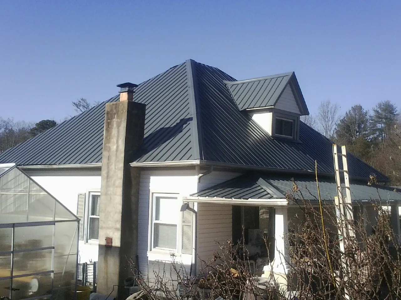 Dark blue standing seam metal roof on a white farmhouse with dormer — Slate & Tile Roof Repair by Roofing Brothers in Asbury
