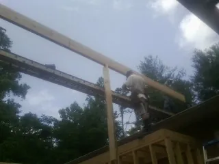 Carpenter setting a ridge beam over a new addition frame — Ice Dam Removal by Roofing Brothers in Asbury