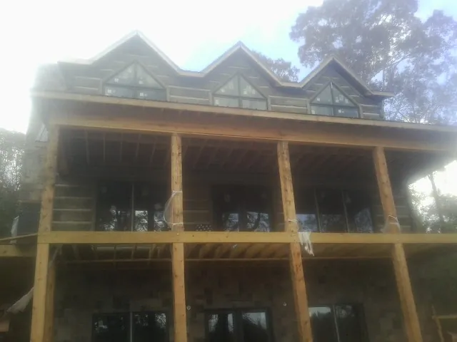 Dormers and porch framing on a large log home under construction — Roof Coating work by our crew in Asbury
