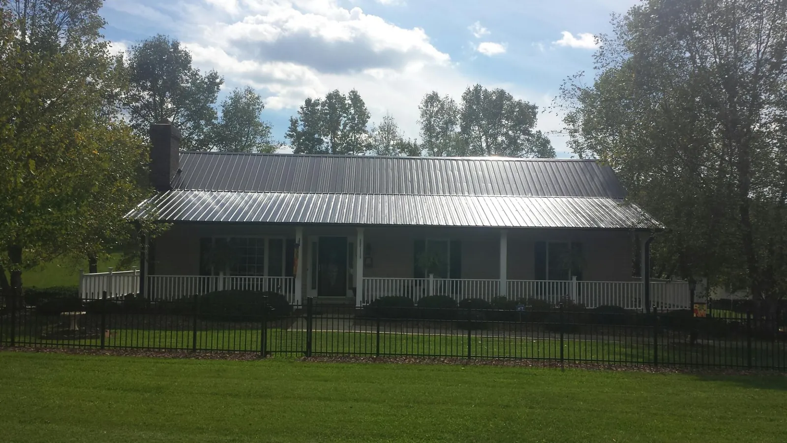 Gray metal roof on a brick ranch with a full width front porch — Gutter Guard Installation work by our crew in Asbury