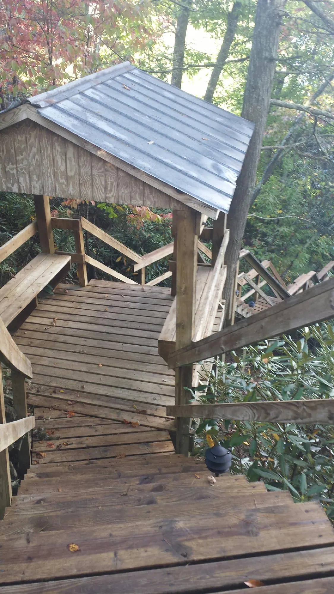Metal roofed shelter over wooden steps on a wooded walkway — Skylight Repair & Installation work by our crew in Asbury